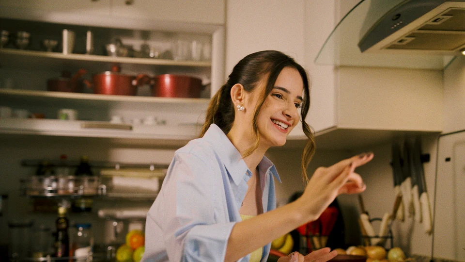 Cena da campanha Raízes para o futuro, com uma mulher sorrindo na cozinha